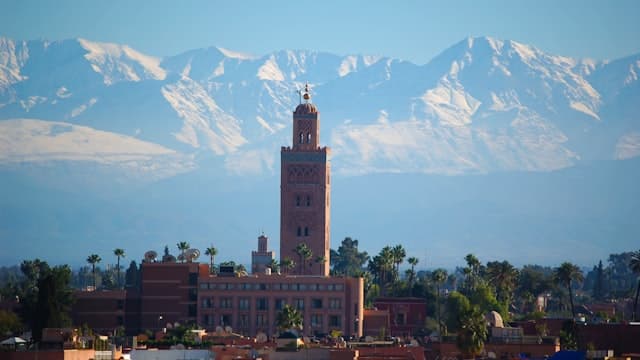 Vue panoramique de Marrakech avec la Koutoubia et les montagnes de l'Atlas enneigées en arrière-plan