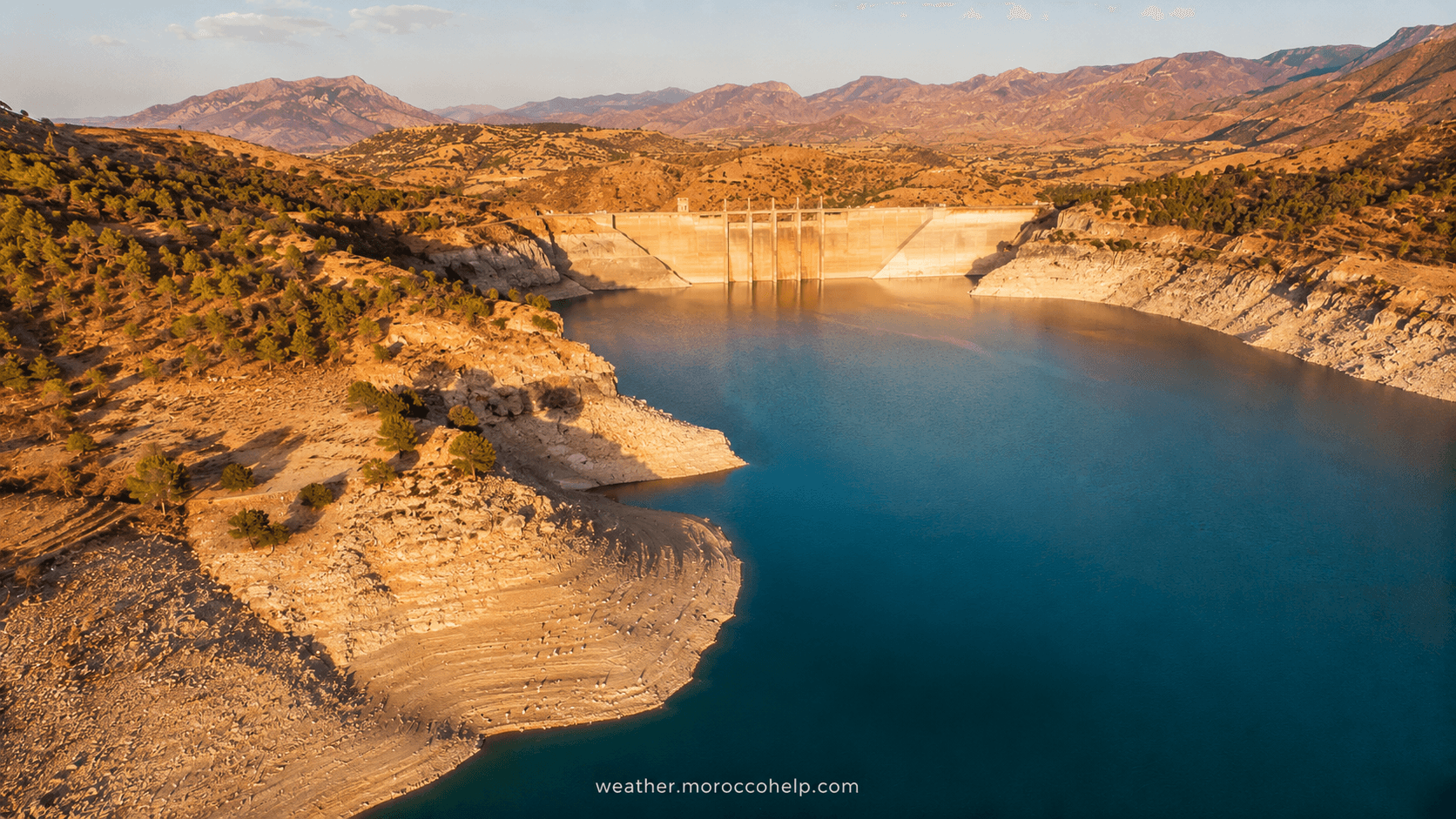 Aerial view of a large Moroccan reservoir in summer, showing receding water lines during the August drawdown